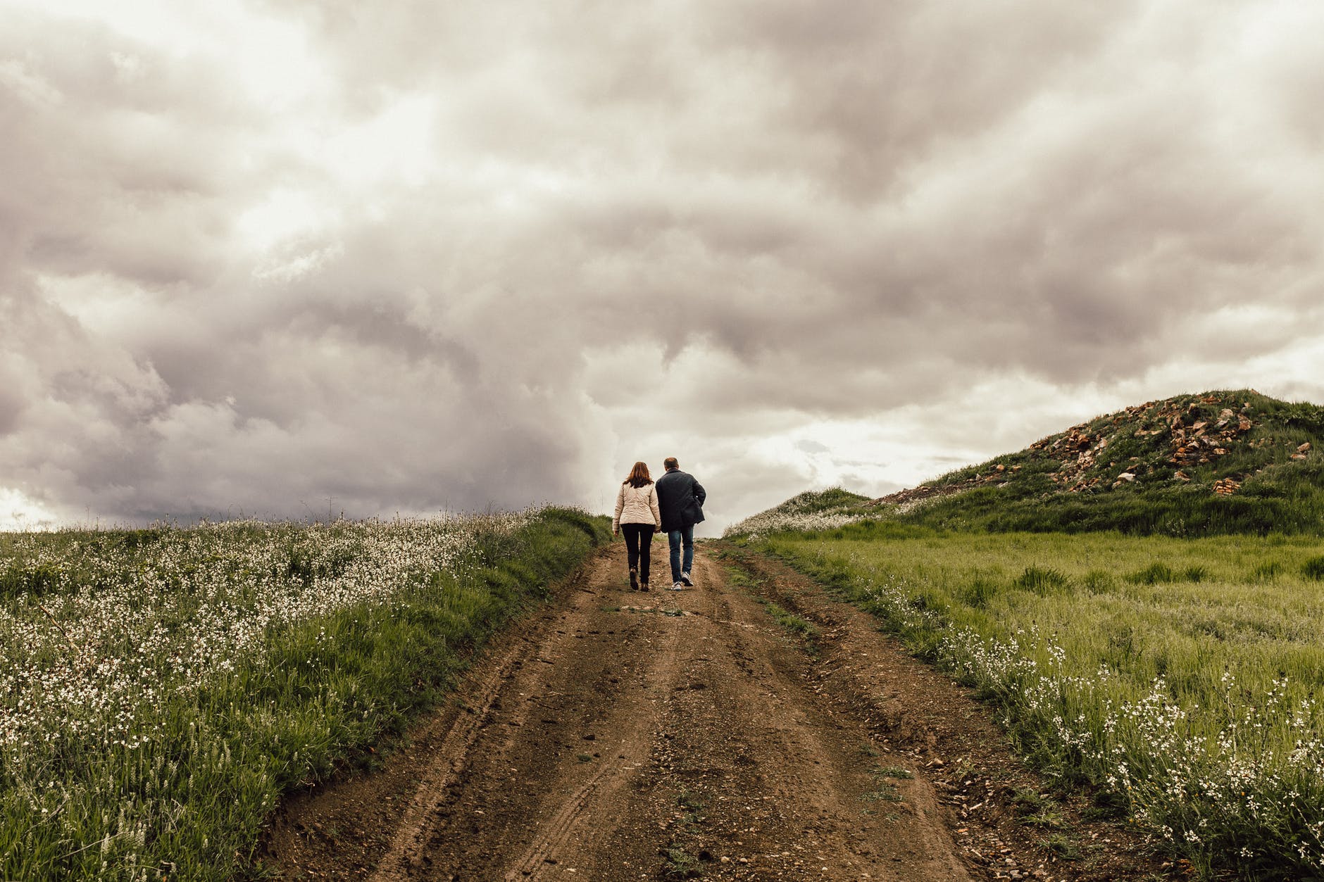 man in black jacket near woman in white jacket surrounded by flowers